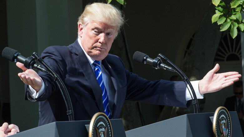 Donald Trump gesturing with open arms in an event