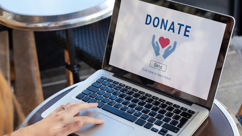 A woman using a computer with a screen image of a donation page.