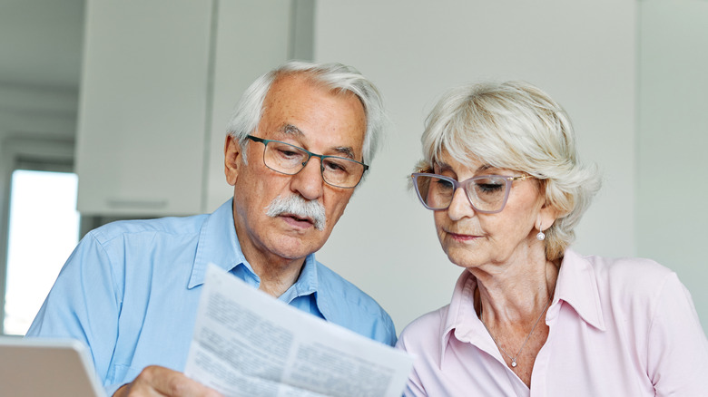 Senior couple checking bills and calculating expenses using a laptop at home.