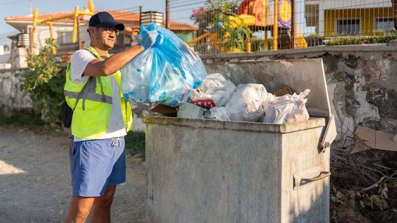 Man in reflective vest throwing trash into a bin