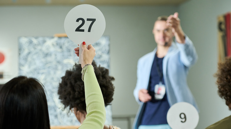 A woman holding up a paddle at an auction.