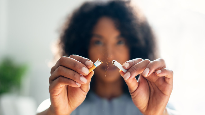 A close-up shot of woman breaking a cigarette in half