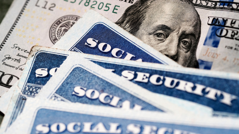Several Social Security Cards on a US United States one hundred dollar bill $100 system of benefits for retired elderly people