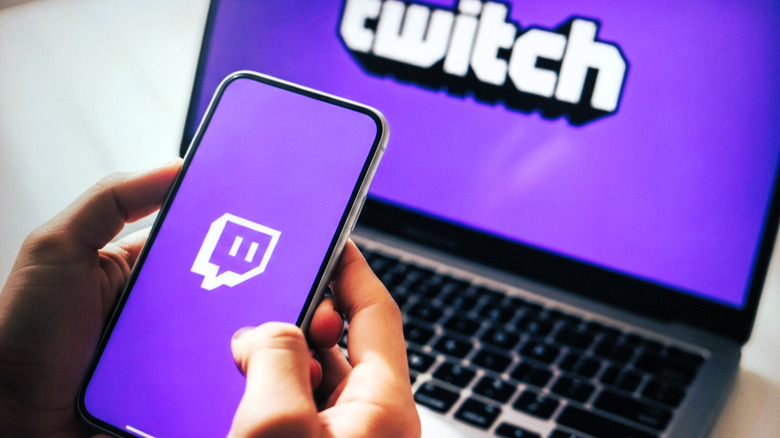 Person holding a laptop with Twitch logo