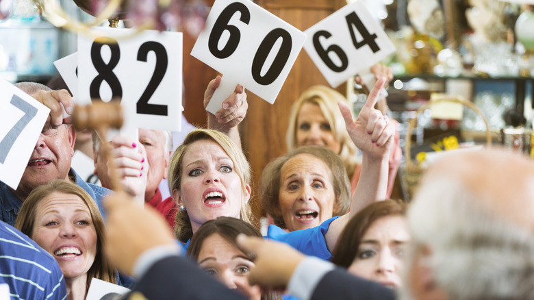 A crowd of excited bidders waving paddles at an auction.
