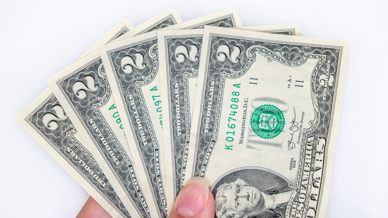 hand holding multiple $2 bills