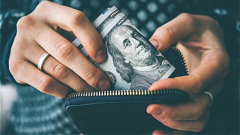 person putting money inside purse