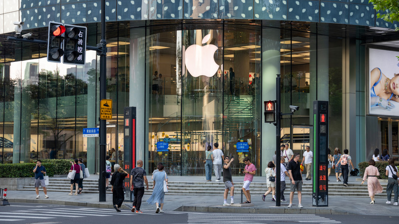 Pedestrians walking in and out of the front door of the Apple Store