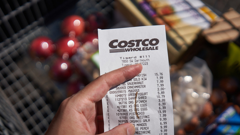 A shopper holds a Costco store receipt outside the warehouse
