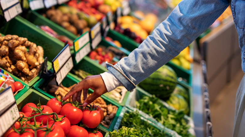 woman's hand reaching for tomatoes in produce department