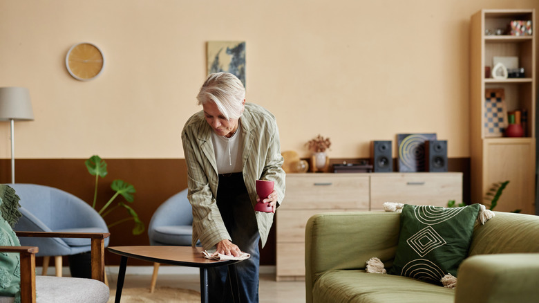 Older woman dusting a well-organized room