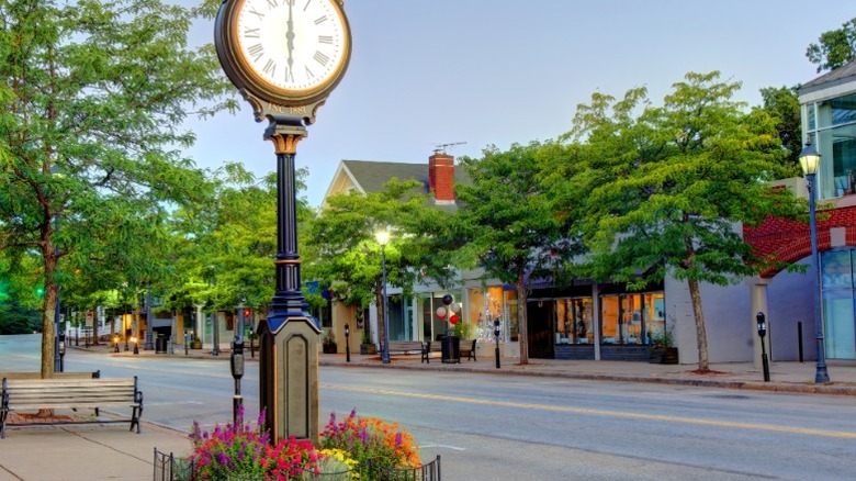 A street lined with shops and trees in downtown Wellesley, Massachusetts with a street clock.