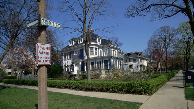 A mansion sized white house on a tre lined street corner in Kenilworth, IL.