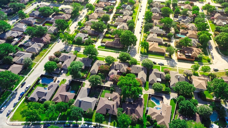 Large two-story suburban houses with swimming pool in upscale residential neighborhood North of Dallas, Texas, lush greenery area of Coppell.