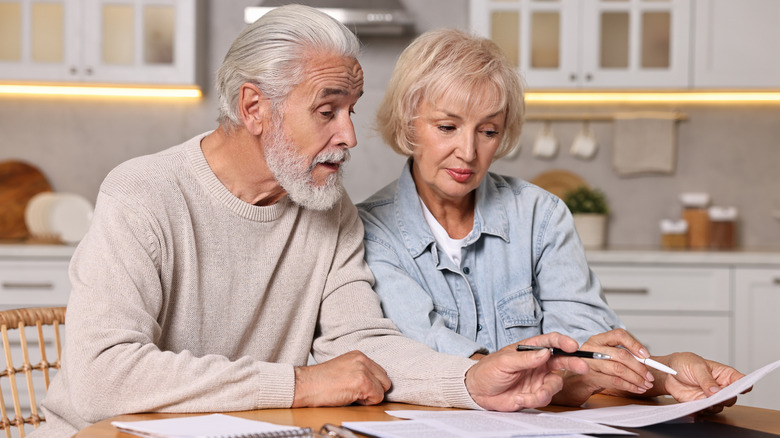 Senior couple planning budget at wooden table indoors