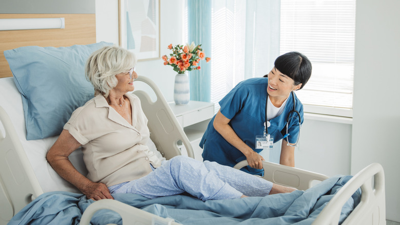 A nurse smiling at an older patient in a hospital bed