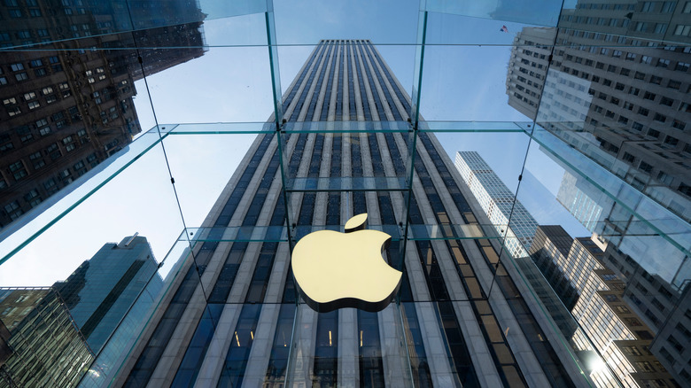 A ground-up view of NYC's flagship Apple store, surrounded by skyscrapers and a blue sky.