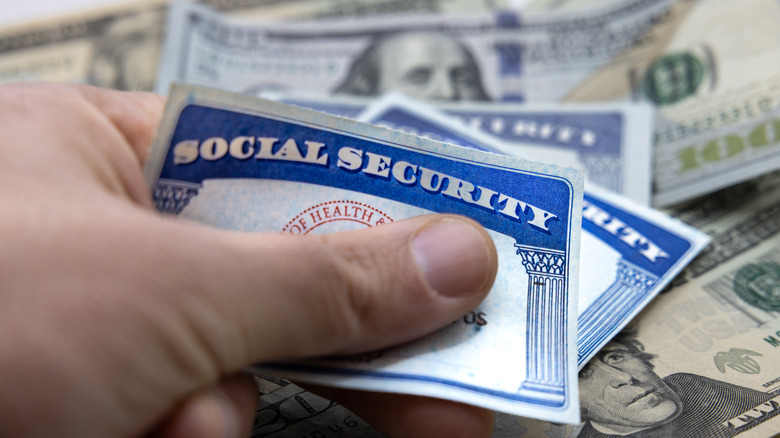 Male hand placing Social Security cards over American dollars