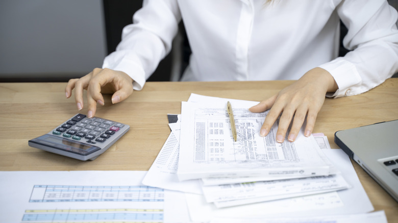 A person calculating bills using a calculator