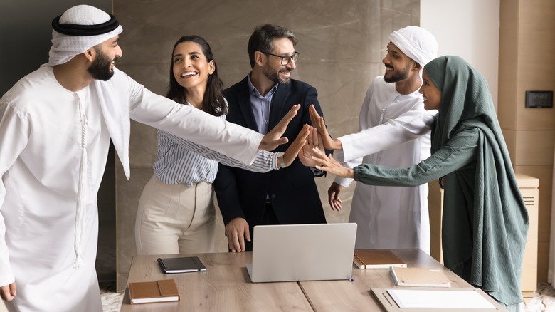Group of people high doing a high five gesture in meeting