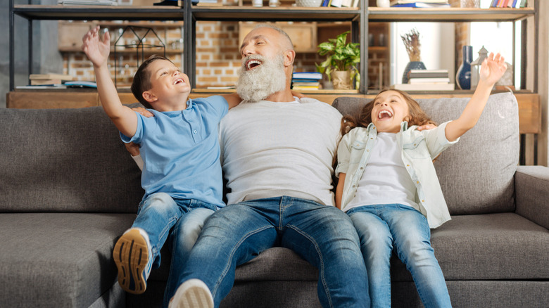 Joyful grandfather with grandkids on sofa