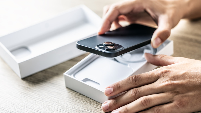 A close up of hands placing a new cell phone in a box.