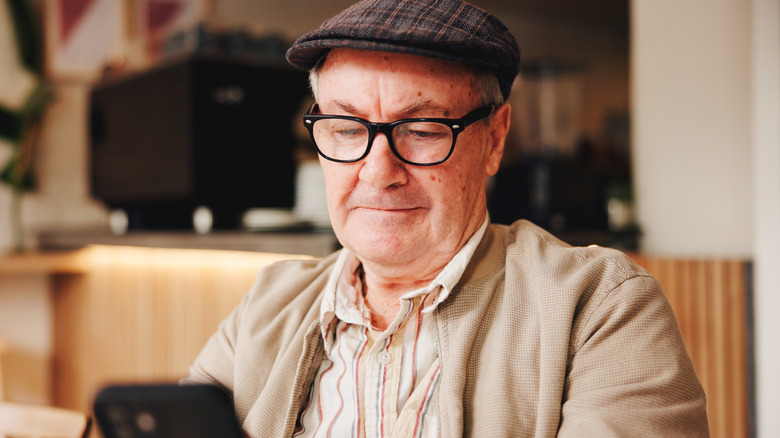 A senior man checks his phone