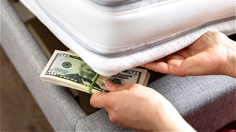 Person putting money under mattress