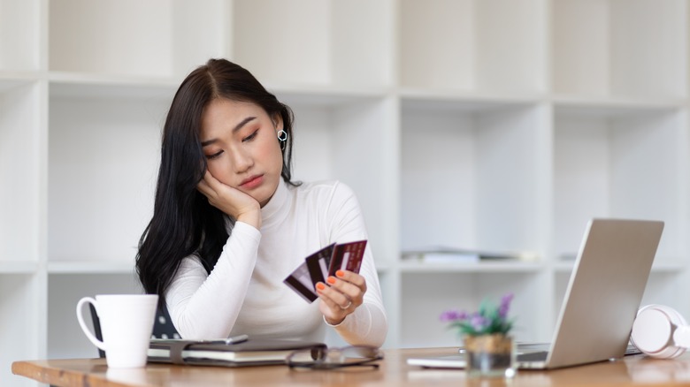 Sad woman holding multiple credit cards