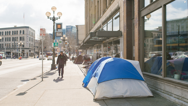 Homeless tents line Seattle street in daytime as man walks by