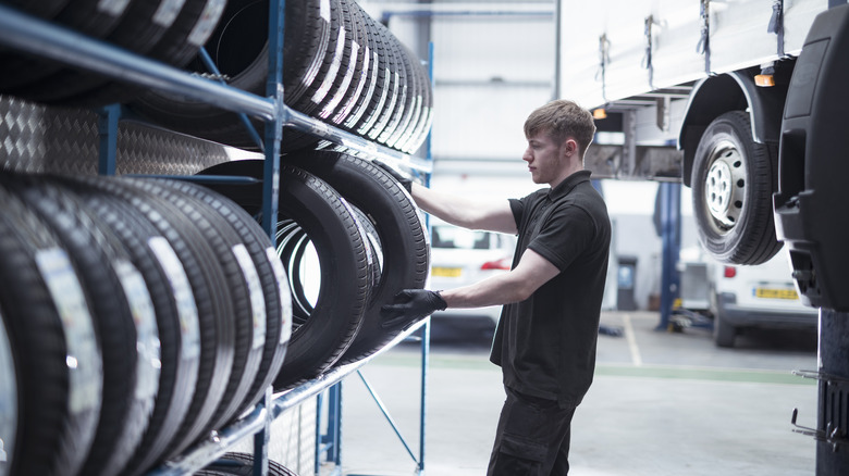 A person pulling out a new tires from a rack