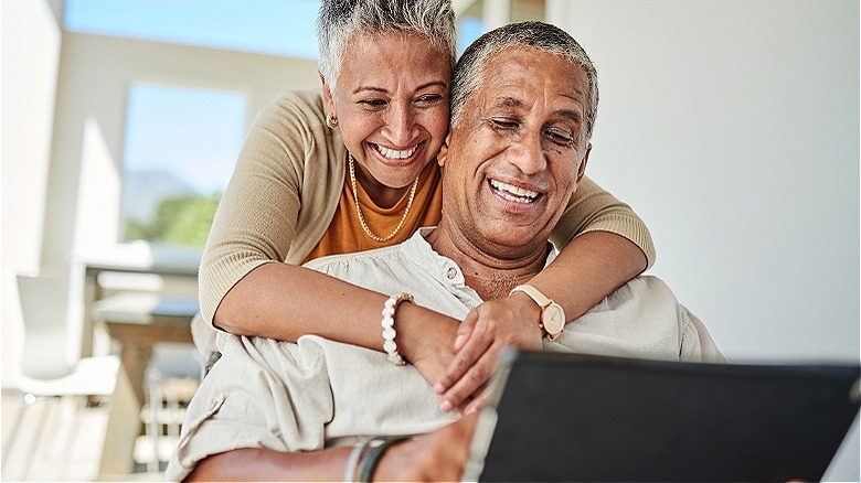 Couple smiling, looking at laptop