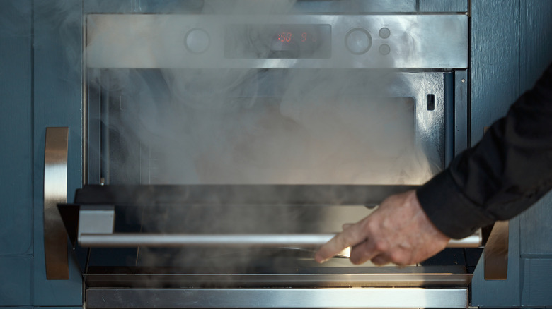person opening the oven door while cooking