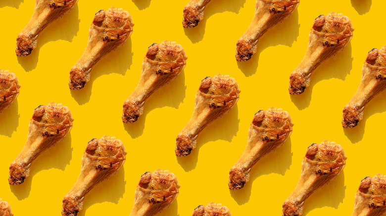 Neatly arranged rows of fried chicken drumsticks on a poppy yellow background.