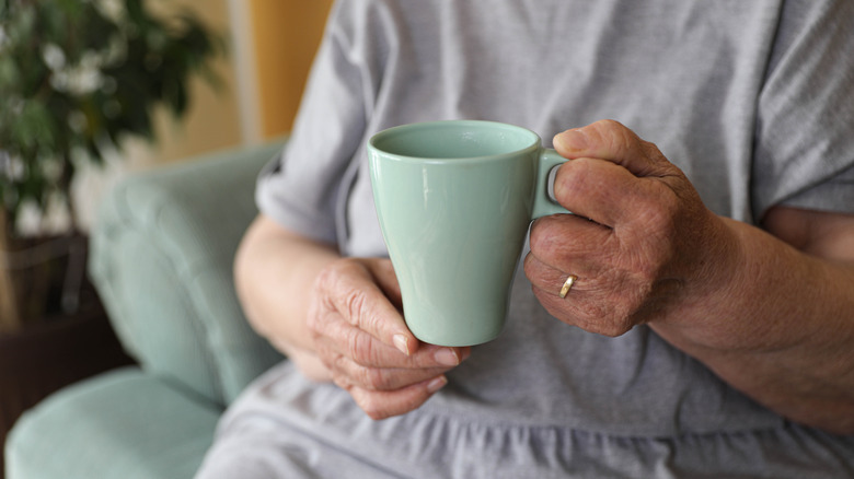 A mature woman's hands holding a mug