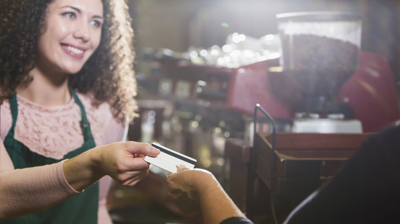 A smiling woman taking a gift card from a customer