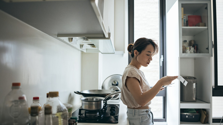A woman looking at a receipt in her kitchen