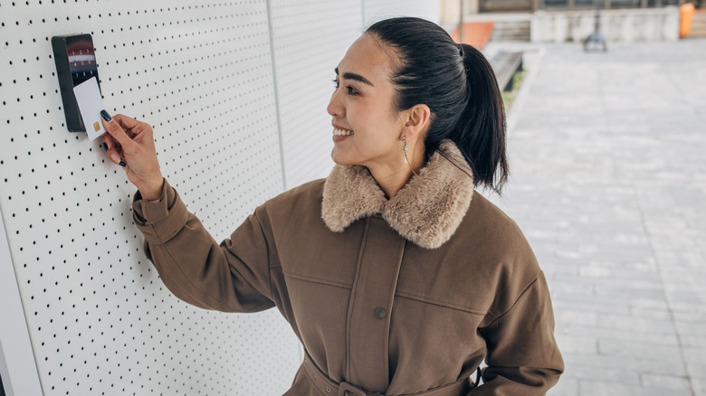 A smiling woman swiping a pass card