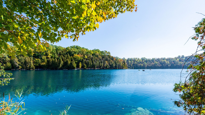 Distant kayakers enjoy the vibrant waters of Syracuse, NY's Green Lakes State Park.