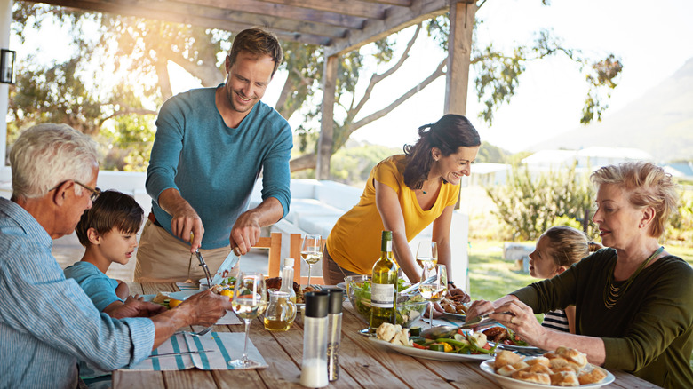 Big family, eating and lunch with food outdoor on patio with conversation