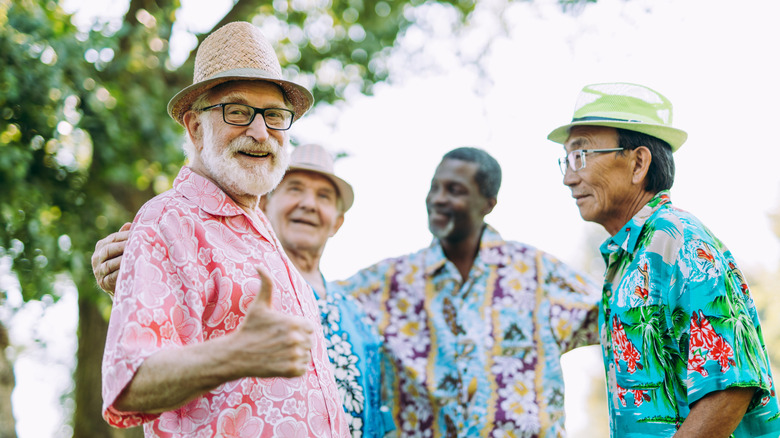 Four old men wearing wearing flowered colored shirts, three of whom with hats.