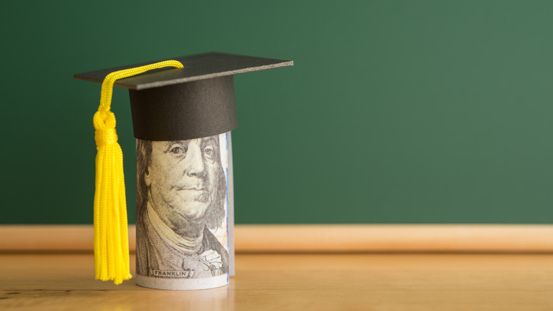 A graduation cap on a rolled up U.S. $100 bill
