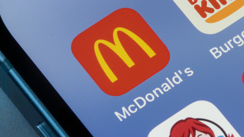 Close-up of a McDonald's App icon on a cornflower blue phone background.