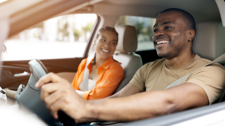 Happy couple smiling in the driver and passenger seats of a car