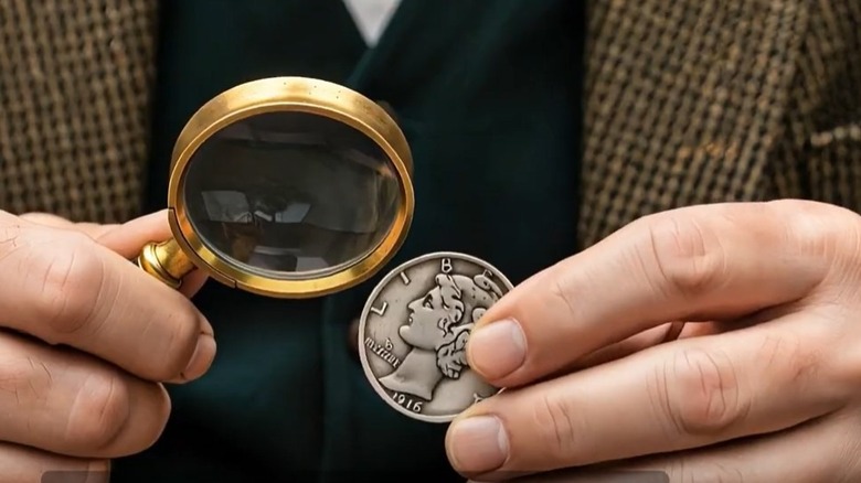 Man examining a 1916-D Mercury dime with a magnifying glass