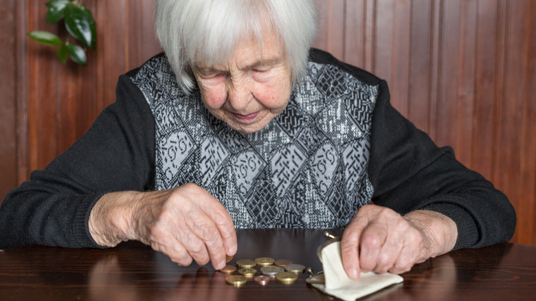 Older woman counts coins on a table