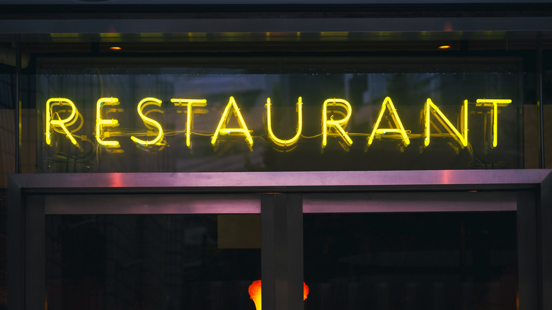 A light-up "Restaurant" sign in an '80s-styled restaurant doorway