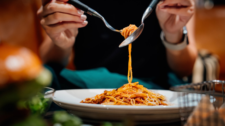 Pasta being twirled on a fork and spoon over dish