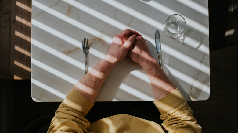 Person sitting at empty dining table