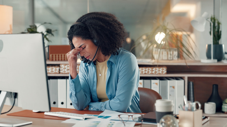 Woman looking stressed at a desk.